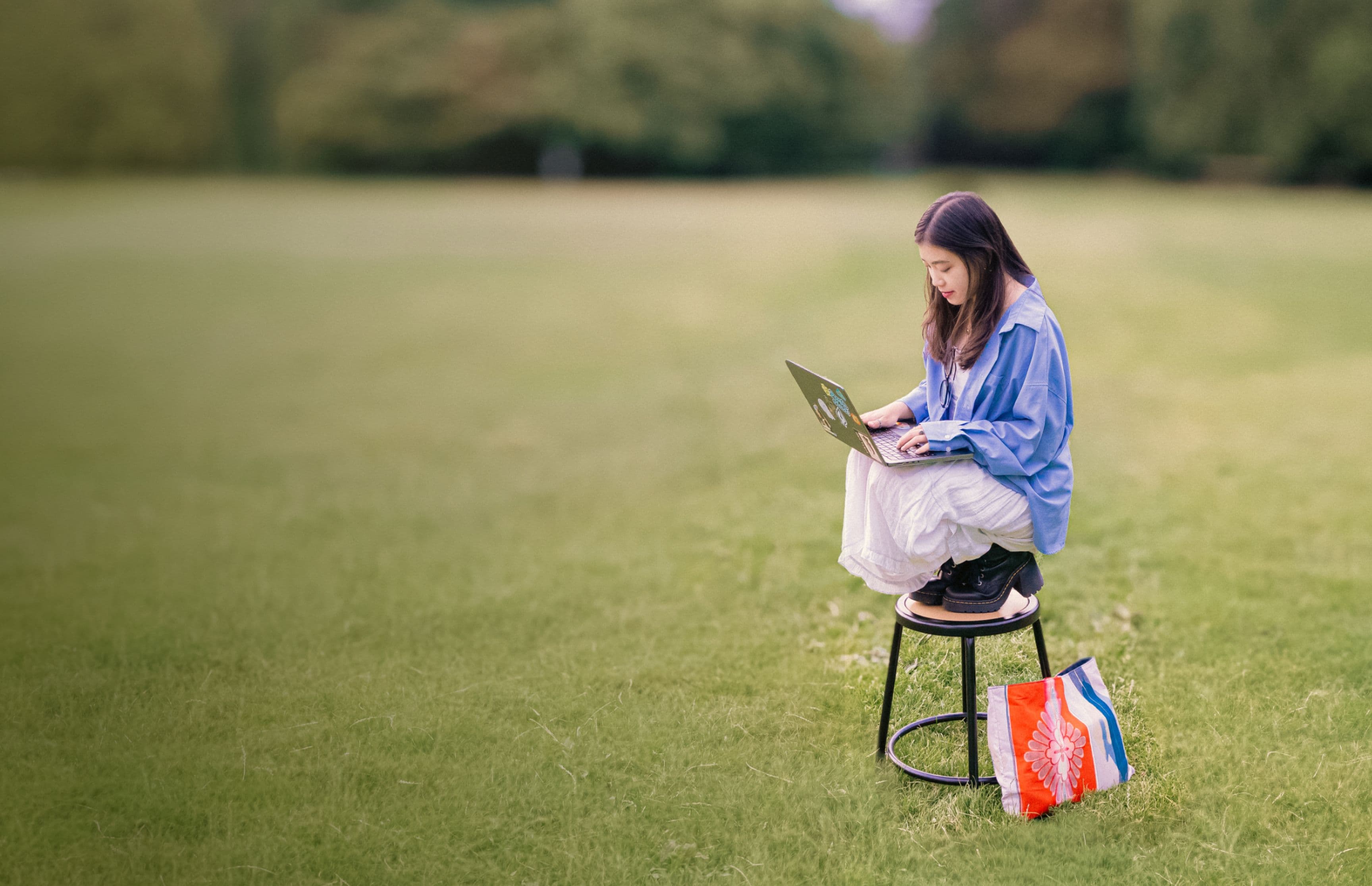 Kelly working on a laptop in a park